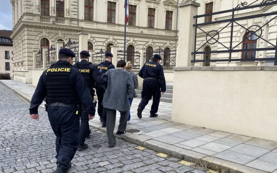 Policisté vedou obviněné cizince do budovy městského soudu, který následně rozhodl o jejich umístění do vazby