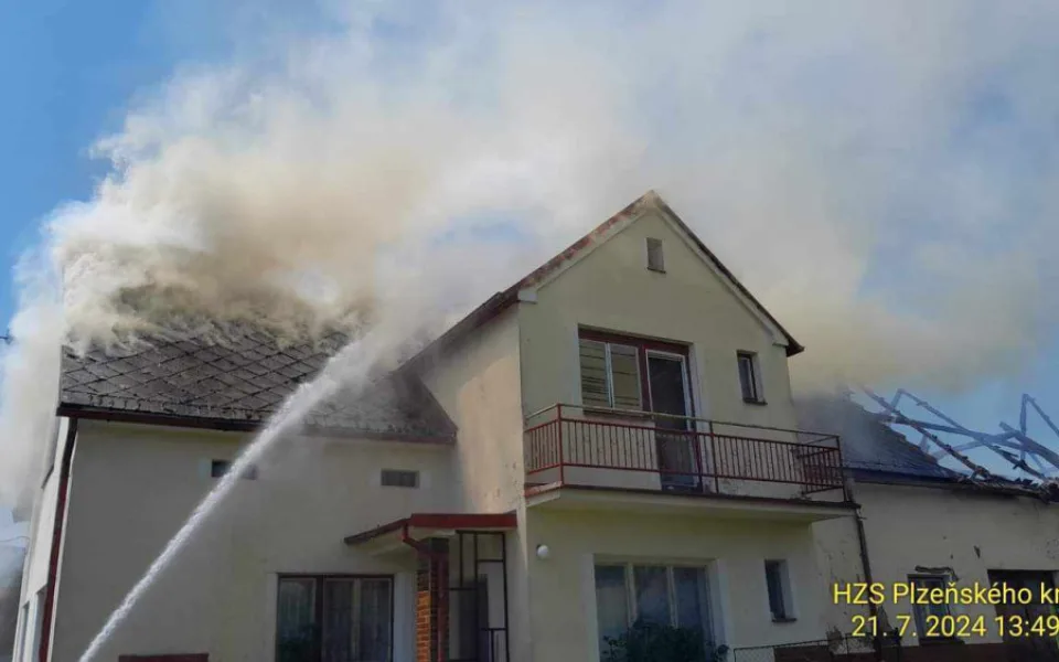 Na Domažlicku hoří hromada pneumatik a okolní budovy, ve vedru kolabují hasiči