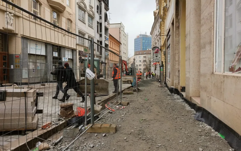 Chodci zmateně přebíhají staveniště.