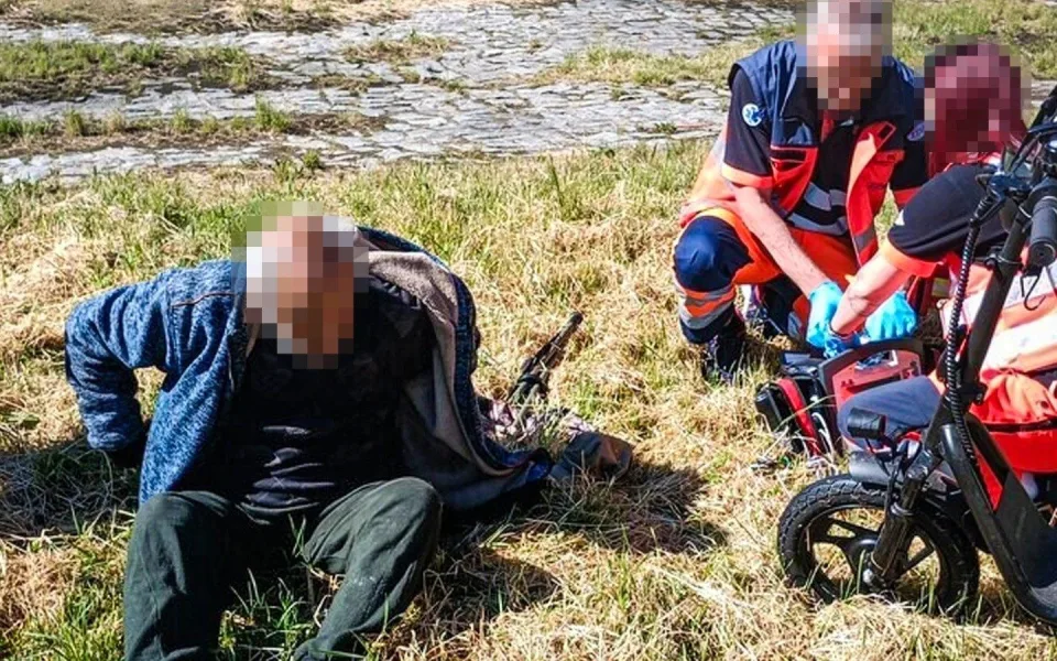 Záchranáři ošetřují rybáře, který zkolaboval u řeky